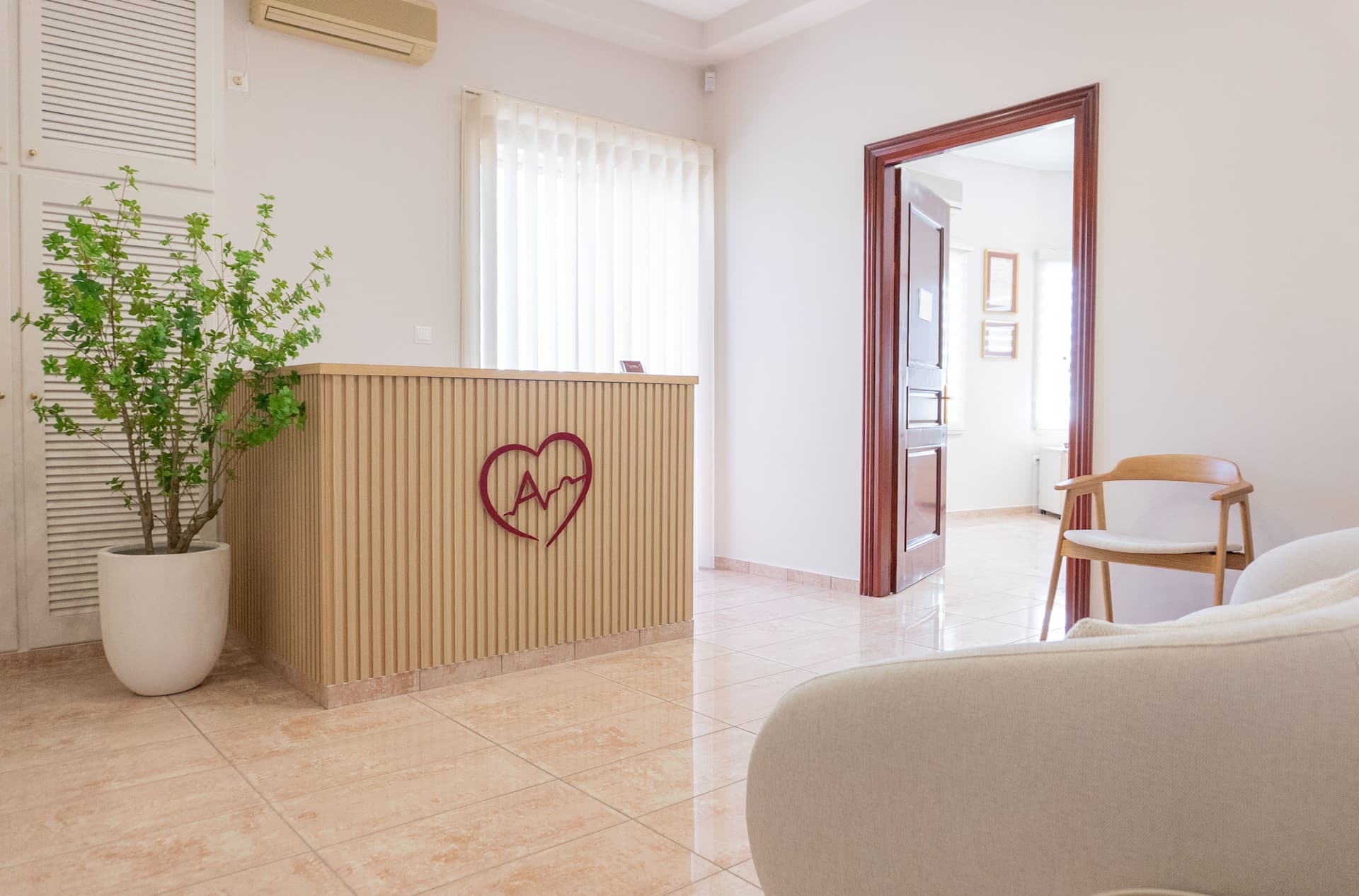 Είσοδος κλινικής. Γραφείο υποδοχής με λογότυπο του ιατρείου στο κέντρο του και φυτό στο πλάι