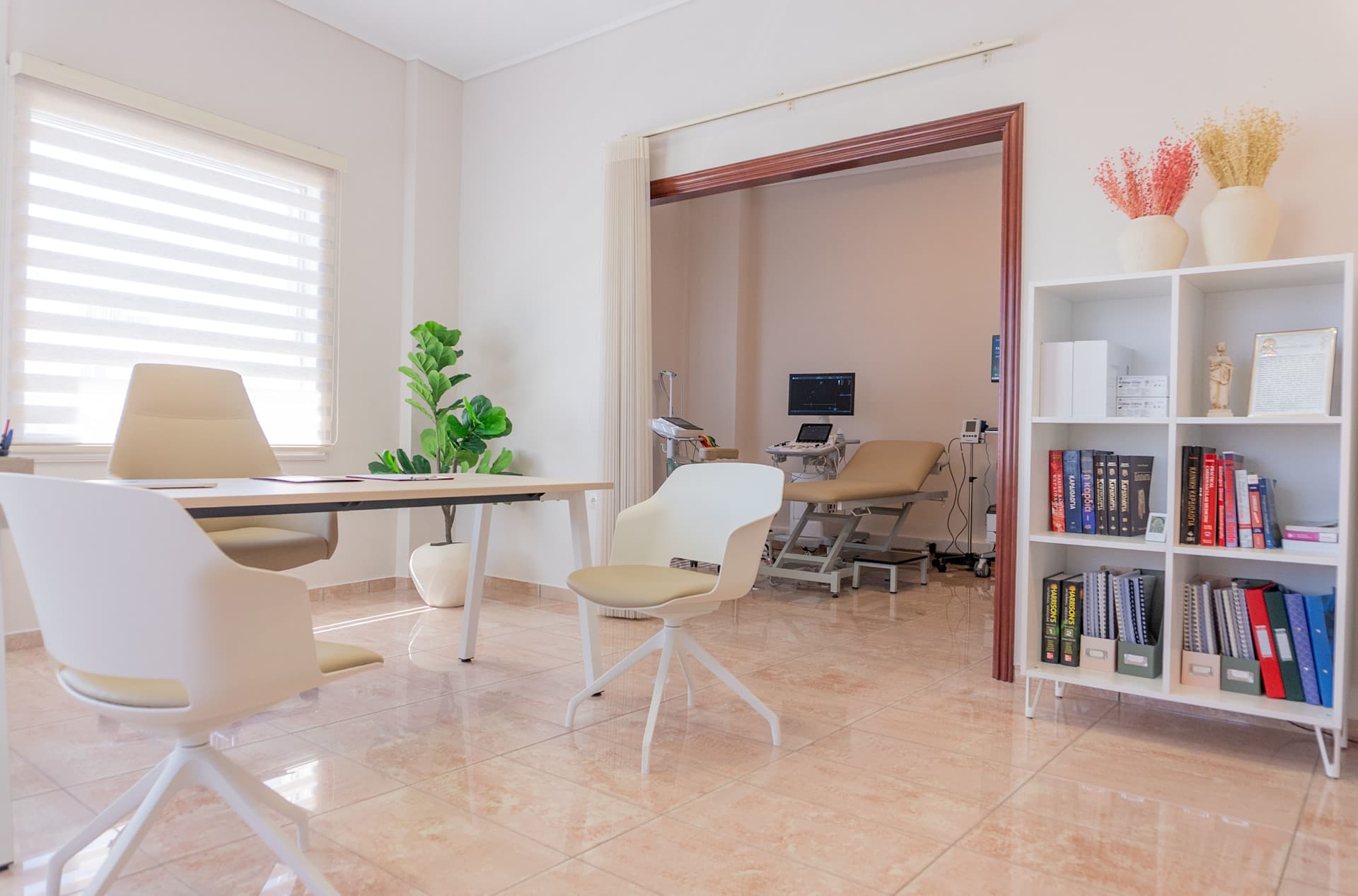 Το γραφείο της ιατρού με δύο καρέκλες επίσκεψης μπροστά του. Το εξεταστήριο είναι ορατό στο βάθος.