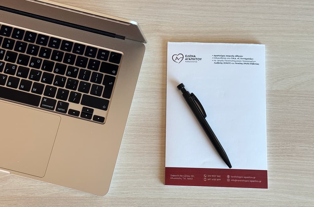 Ο φορητός υπολογιστής και το μπλοκάκι με το στυλό της ιατρού στο πλάι